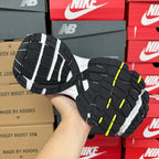 Unisex running shoe outsole, black tread with white midsole and lime-yellow marks