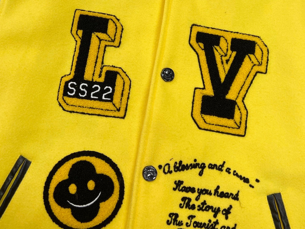 Yellow Louis Vuitton jacket close-up with black graphic letters, smiley emblem, snap buttons
