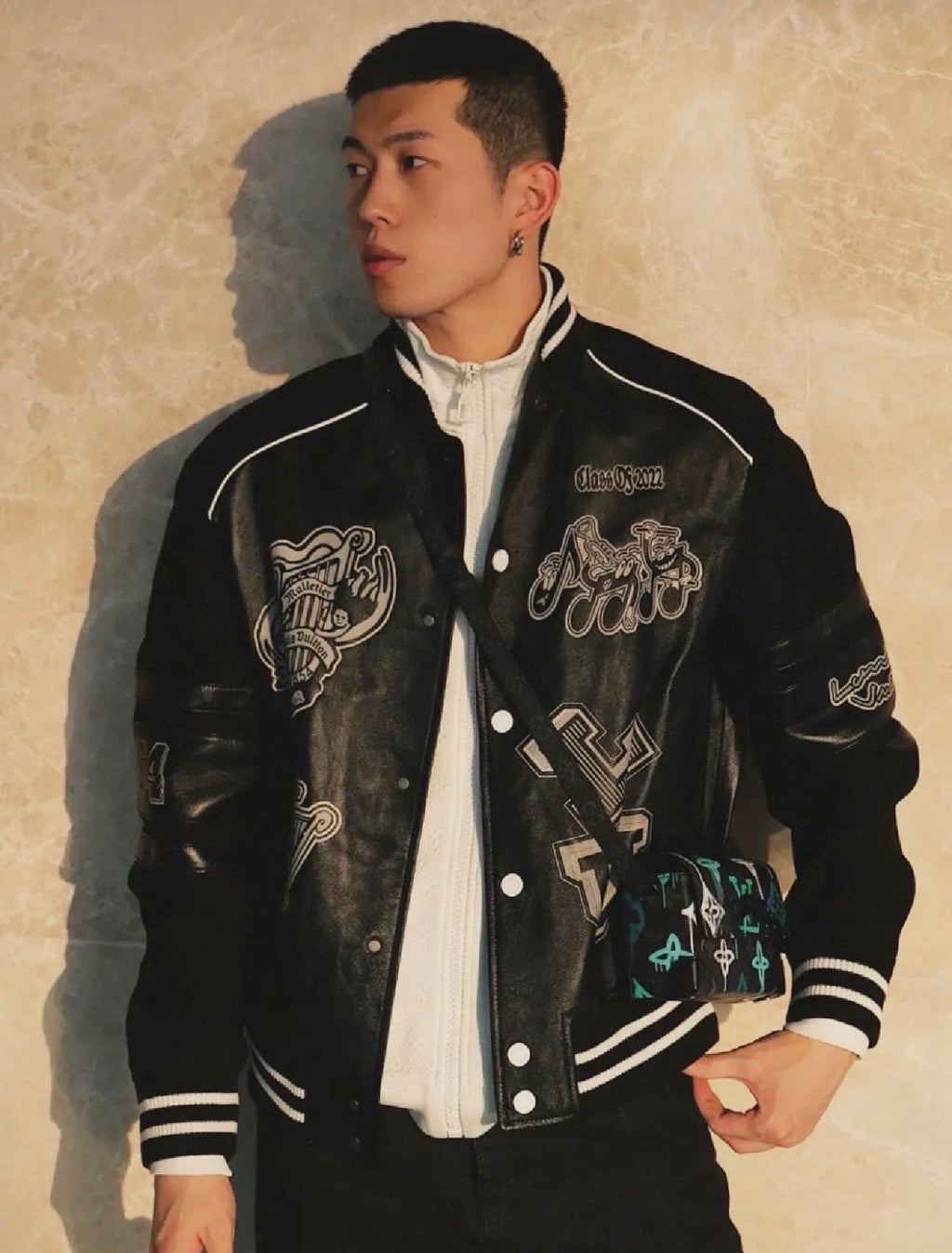 Varsity jacket by Louis Vuitton, black with white trim, snap front, and graphic patches