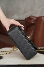 Chanel quilted black clutch-style handbag with gold zipper and chain