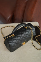 Chanel quilted black mini handbag with curved top handle and gold chain