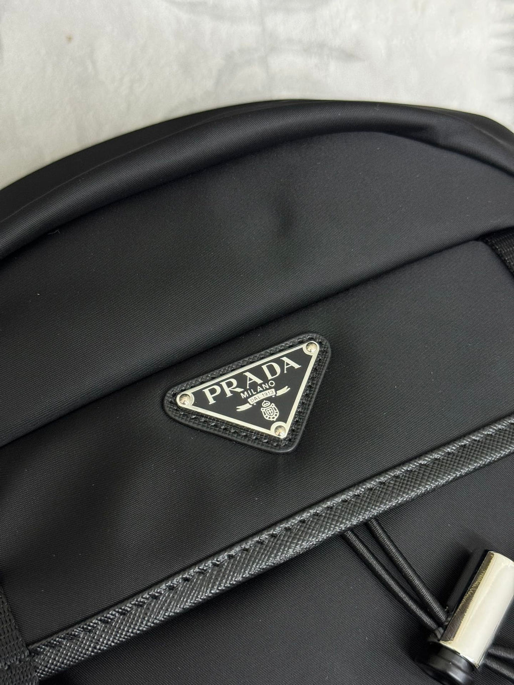 Prada logo patch on black nylon backpack flap with textured trim