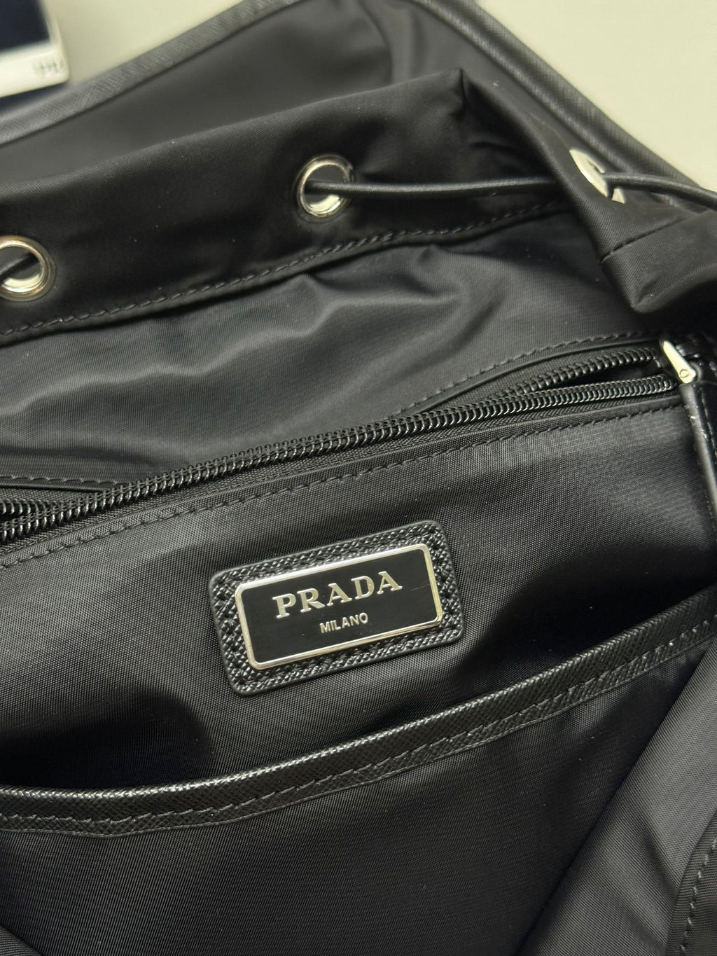 Prada Milano logo patch on black backpack front pocket with zipper