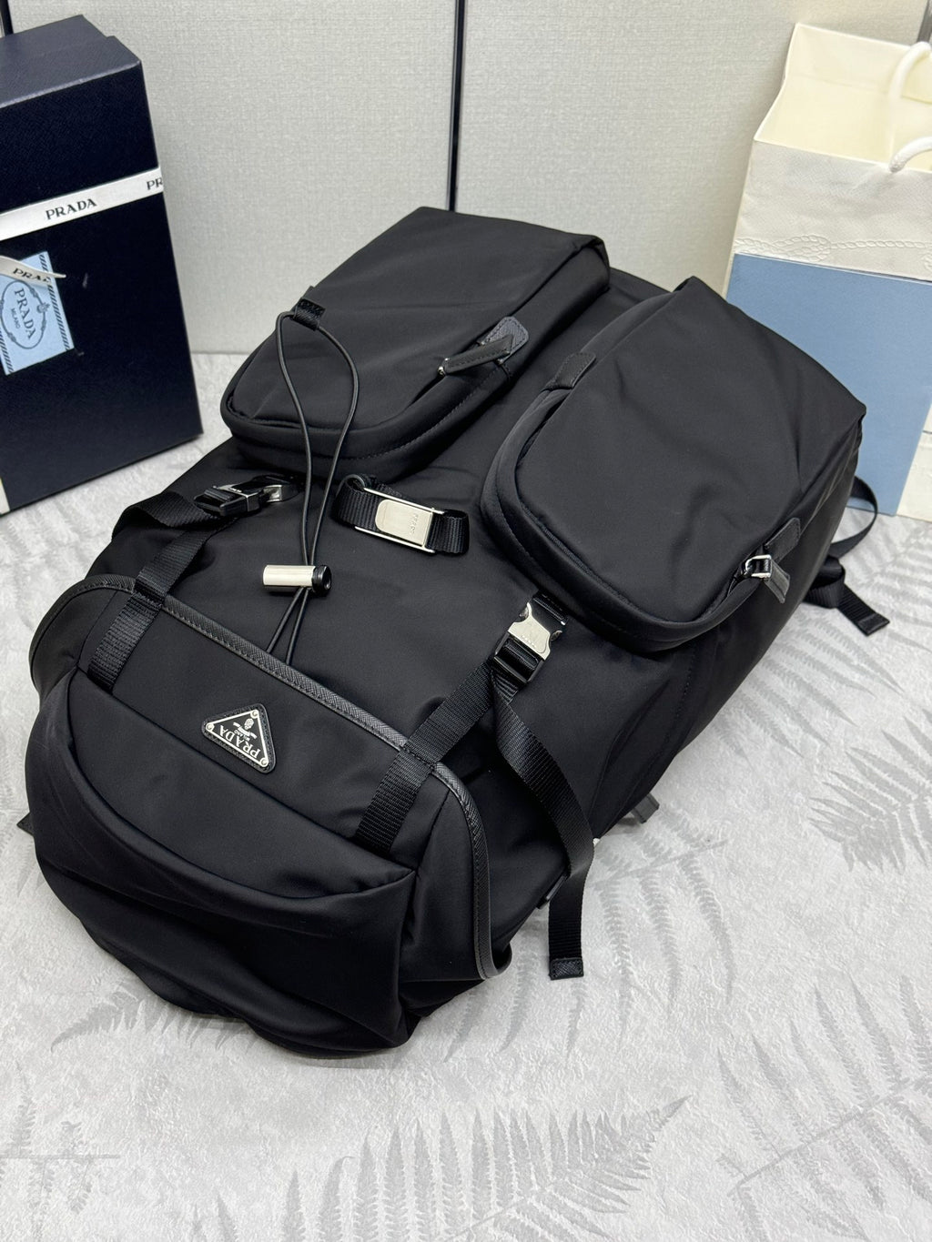 Prada black nylon backpack with top handle, buckles, and front pockets