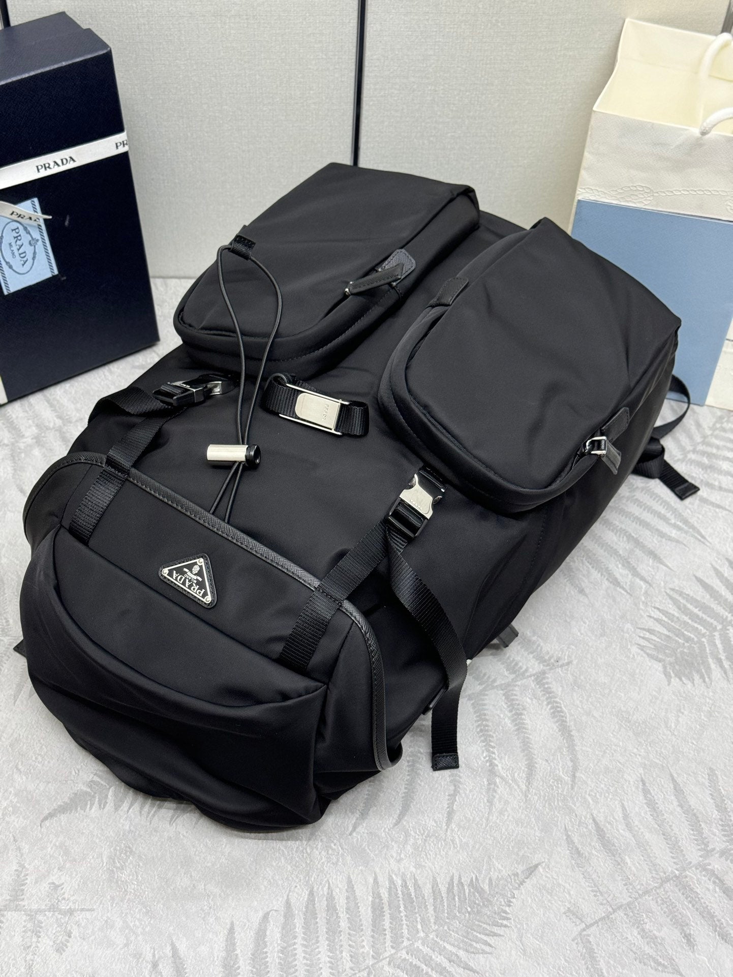 Prada black nylon backpack with top handle, buckles, and front pockets