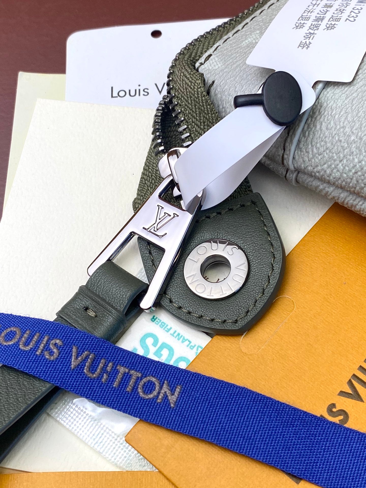 Louis Vuitton key holder accessory with silver clasp and black ring on card