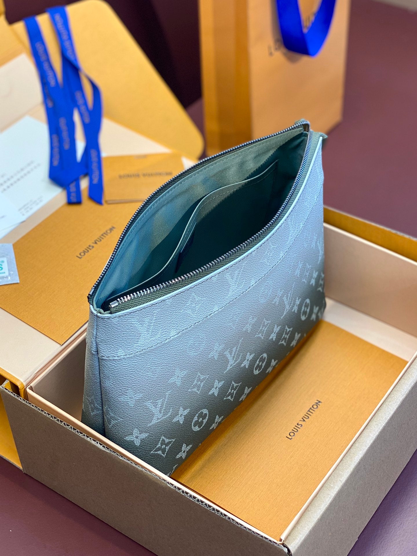 Louis Vuitton monogram wristlet bag open, showing teal interior lining and zipper