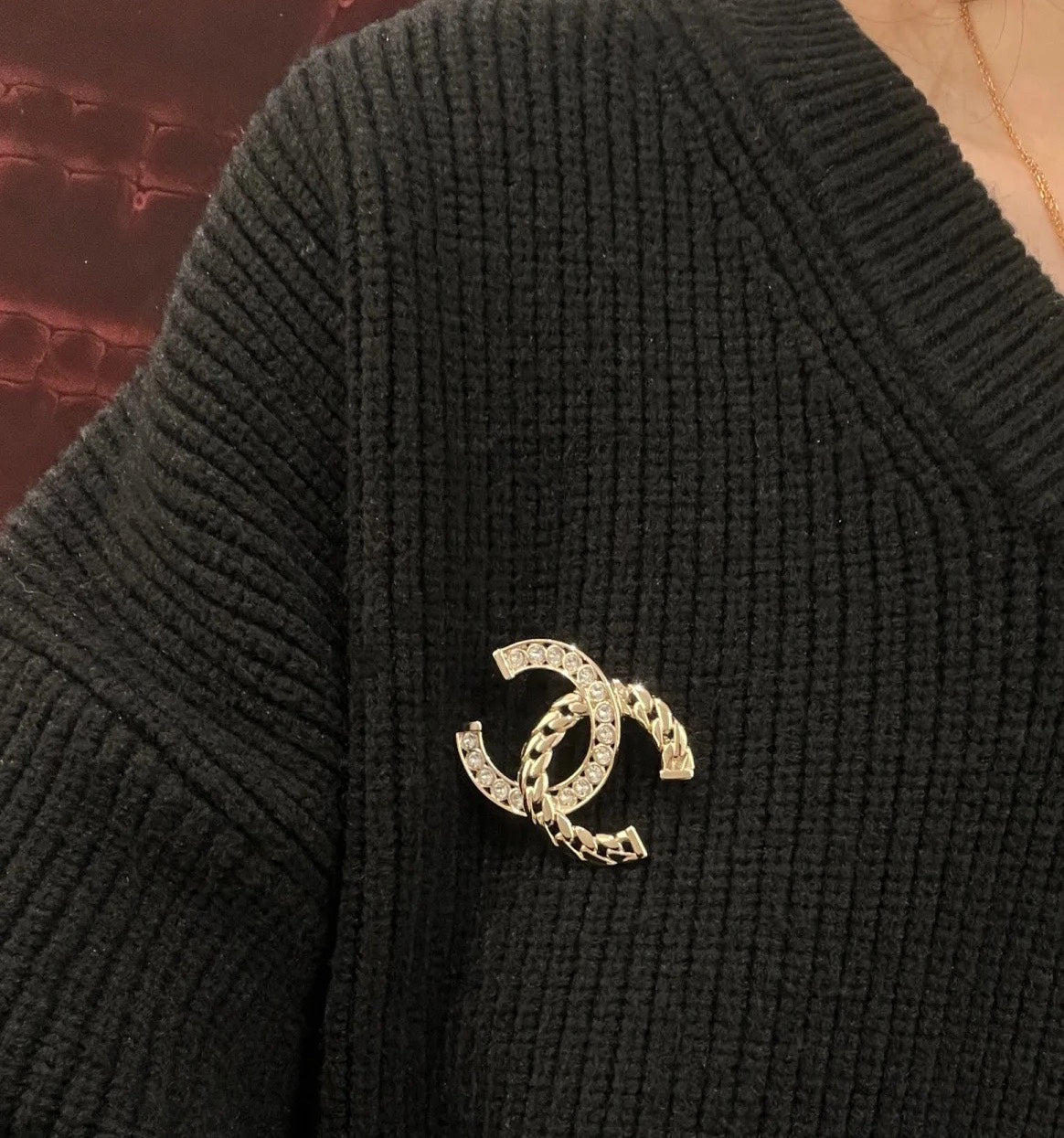 Gold-tone C brooch with clear rhinestone accents on dark knit fabric