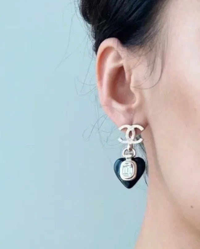 Chanel earrings with black heart charm and clear crystal center, shown on ear