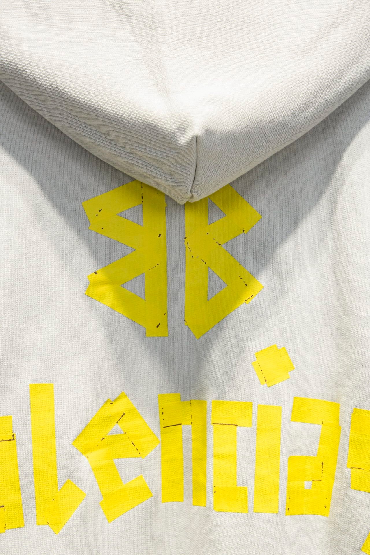 Off-white hoodie close-up with hood seam and yellow logo graphic