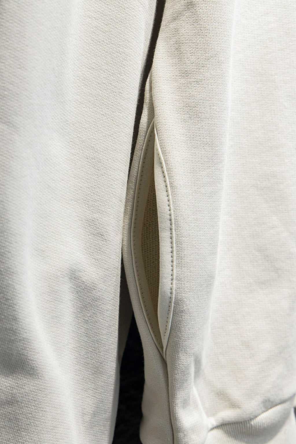 Off-white hoodie side view with sleeve seam and curved hem