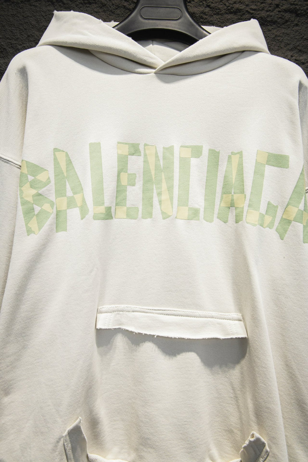 Off-white hoodie front with hood and light-green logo graphic across chest