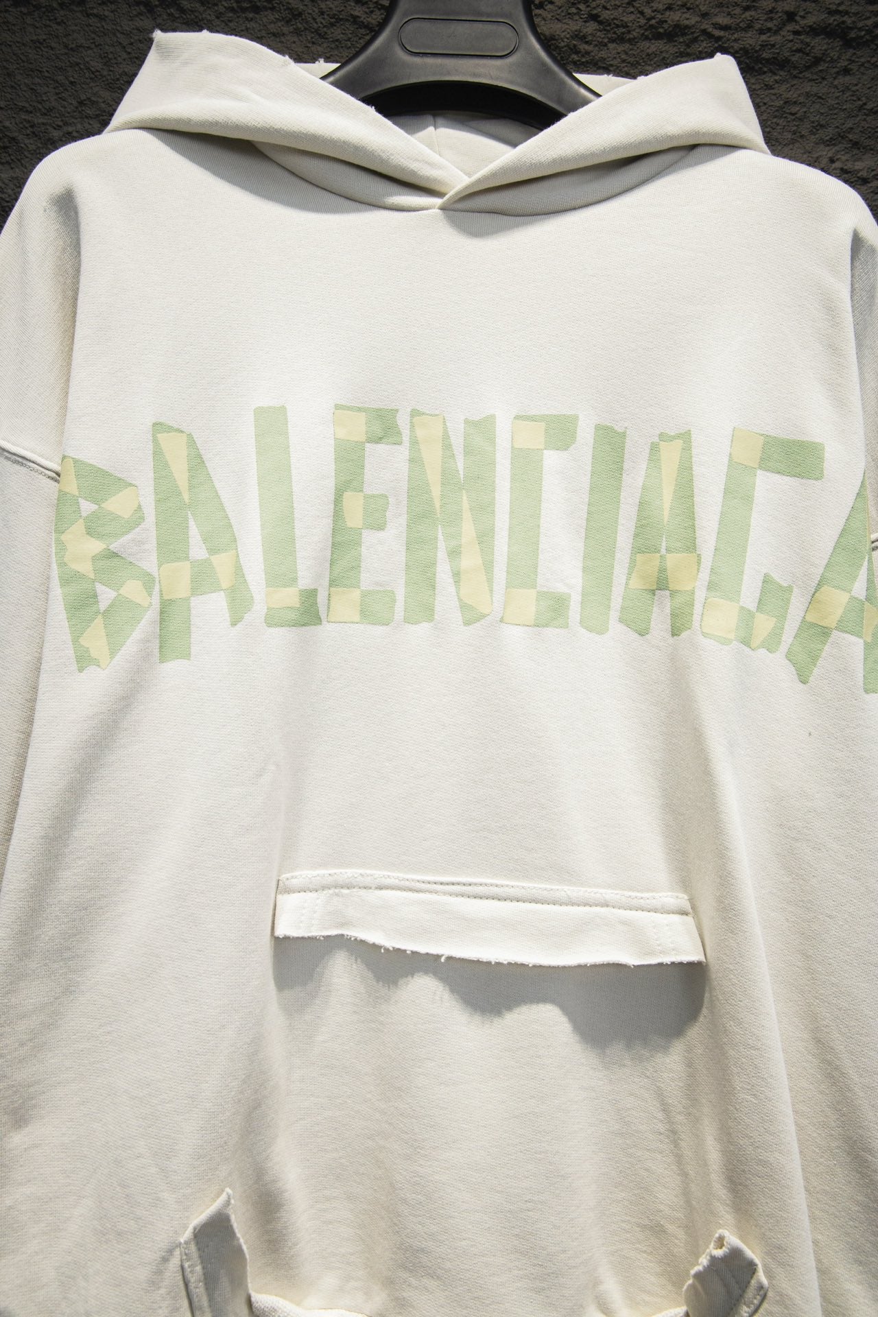 Off-white hoodie front with hood and light-green logo graphic across chest