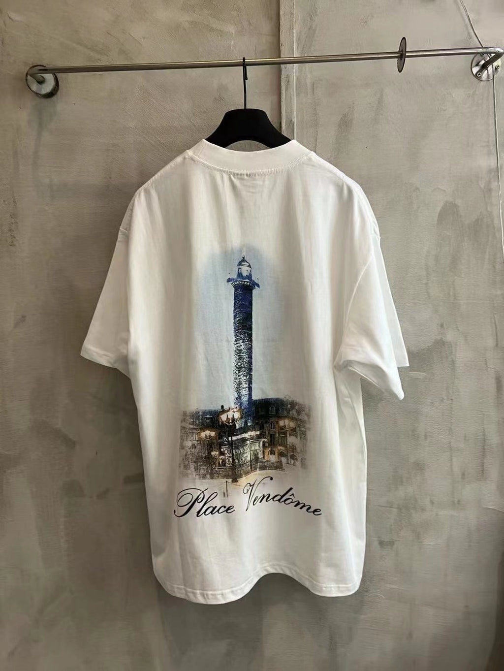White crewneck T-shirt with blue tower and 'Place Vendome' back graphic.