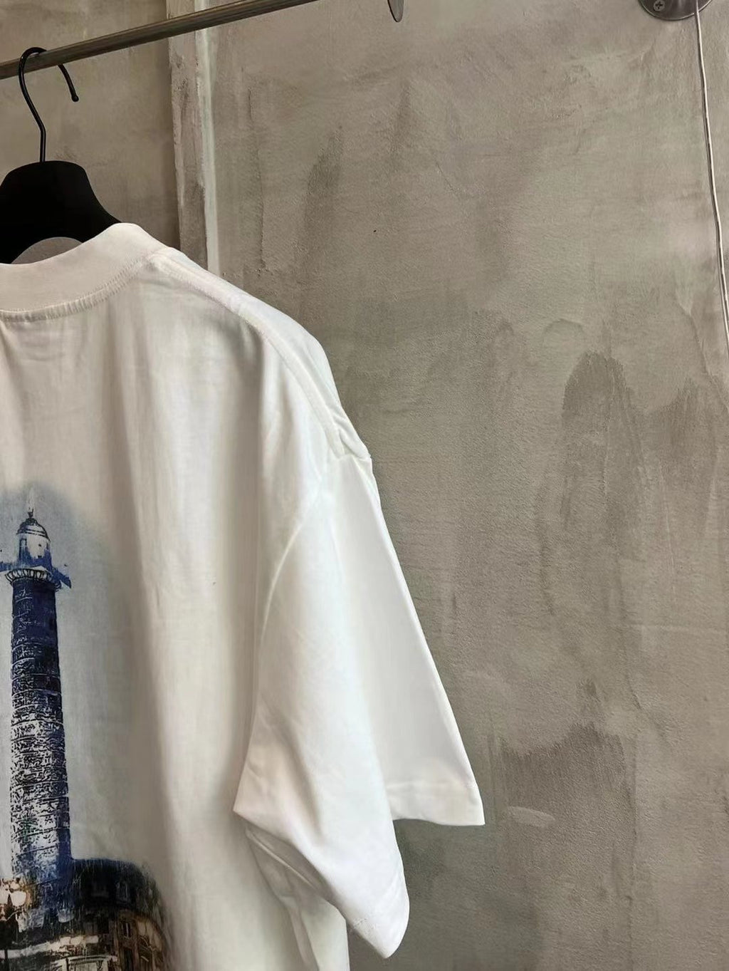 White crewneck T-shirt with blue tower graphic on the back.