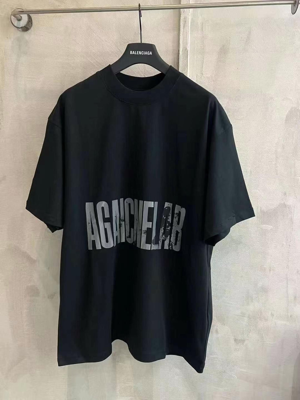 Black crew-neck T-shirt with large distressed “AGAINST” graphic print on the front