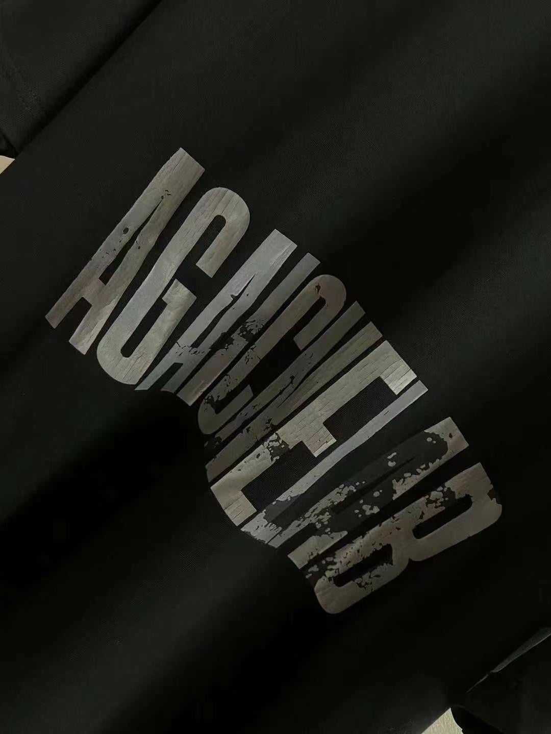 Close-up of black T-shirt sleeve with distressed “AGAINST” graphic print