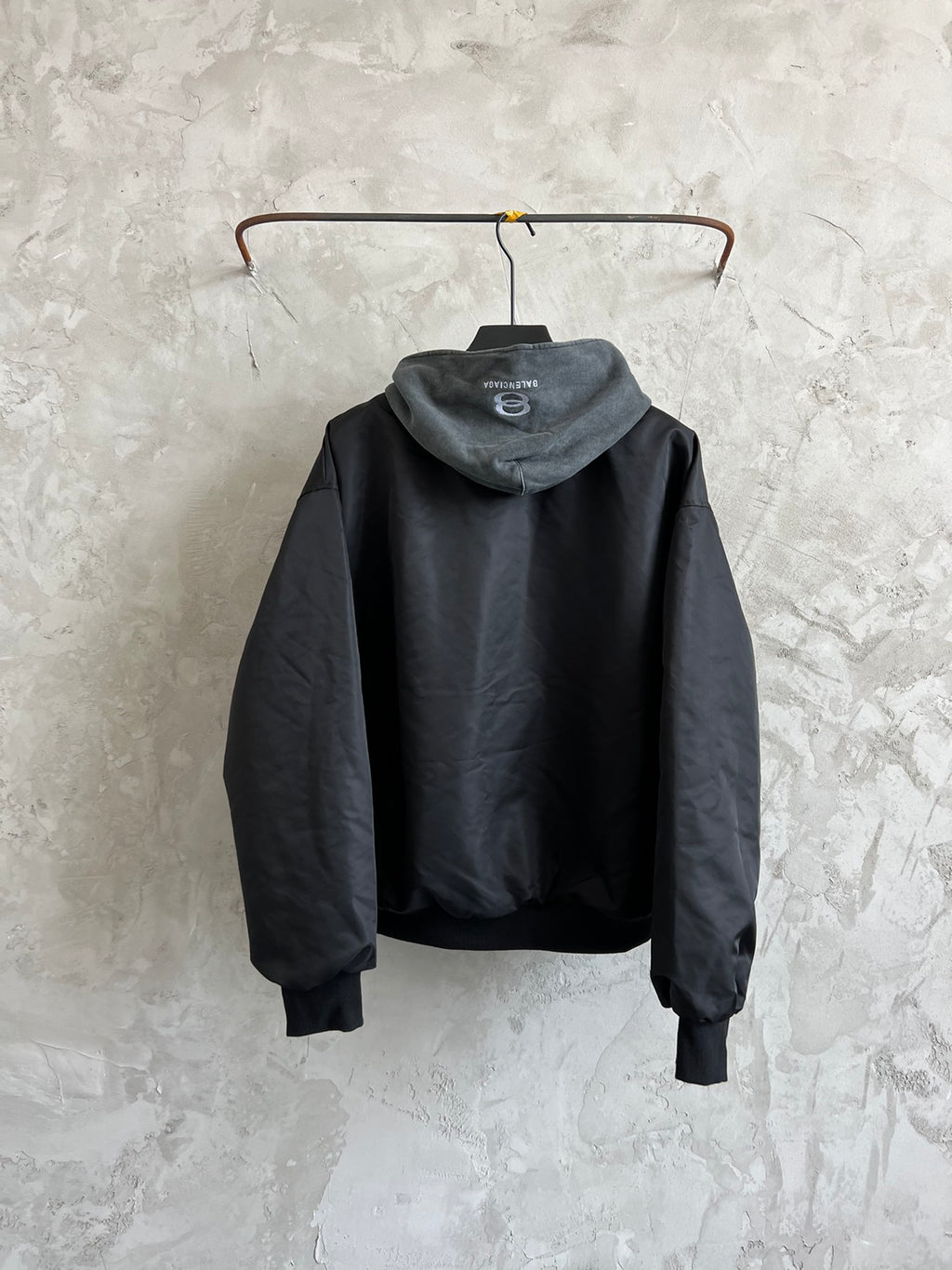 Dark hooded zip jacket back view with heather gray hood and ribbed cuffs
