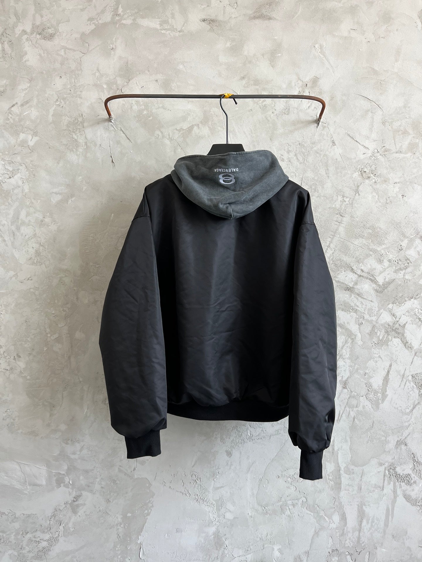 Dark hooded zip jacket back view with heather gray hood and ribbed cuffs