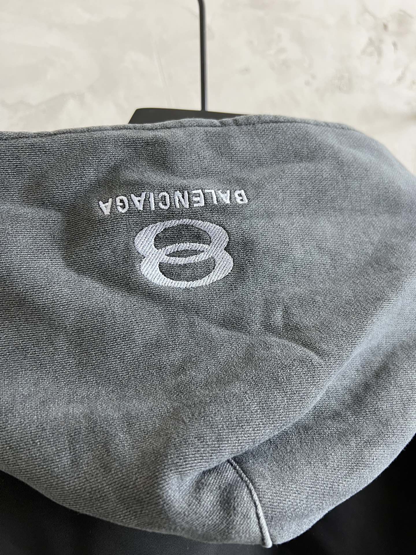 Back of heather gray hood with BALENCIAGA 8 logo on dark jacket