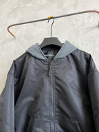 Dark hooded zip jacket with heather gray hood, ribbed cuffs, hanging tag