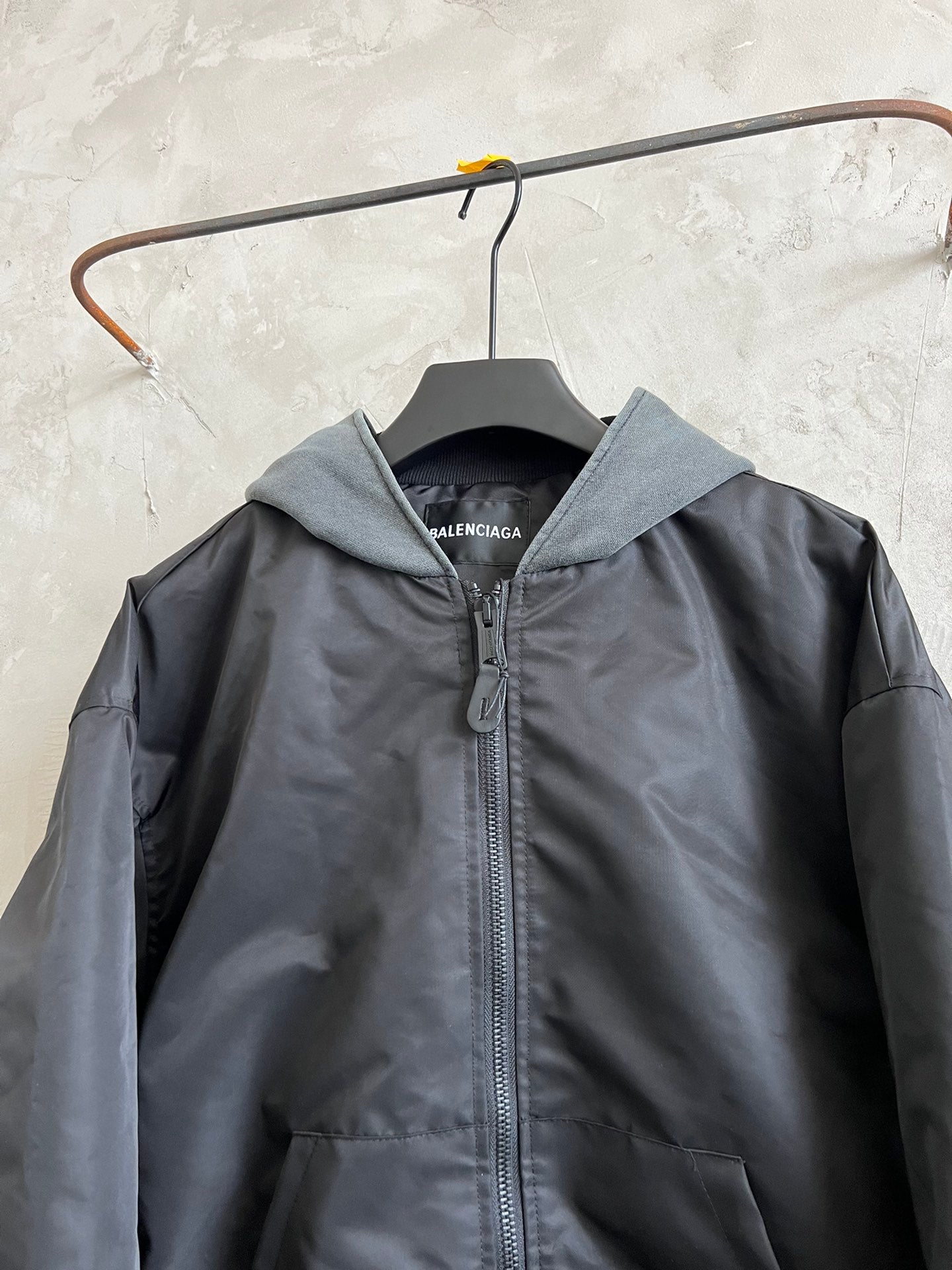 Dark hooded zip jacket with heather gray hood, ribbed cuffs, hanging tag