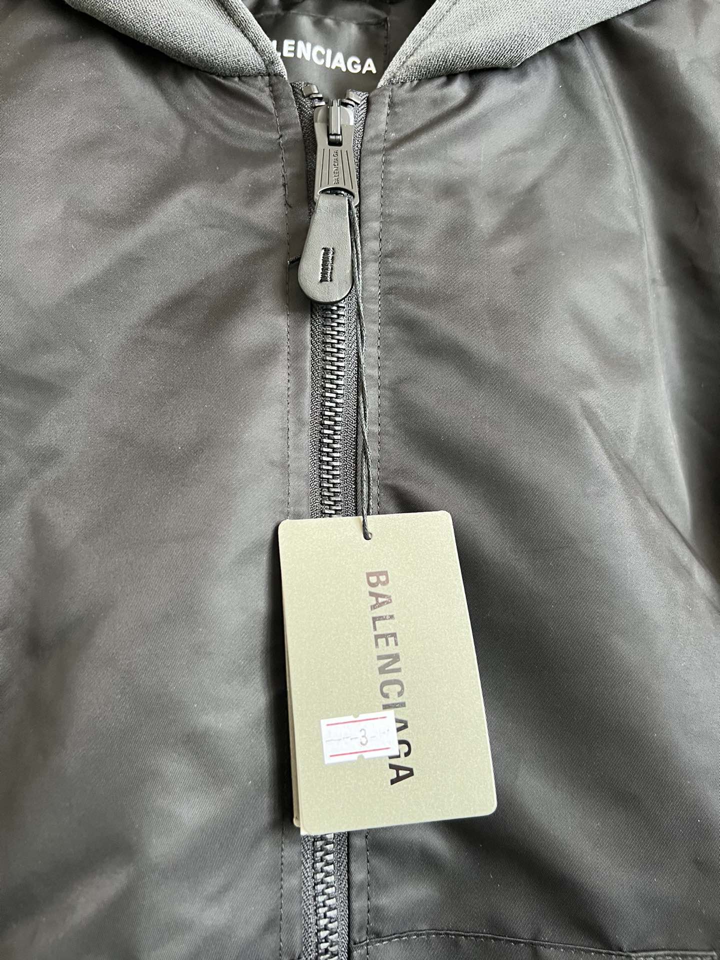 Dark zip hooded jacket with metal zipper and beige brand hang tag