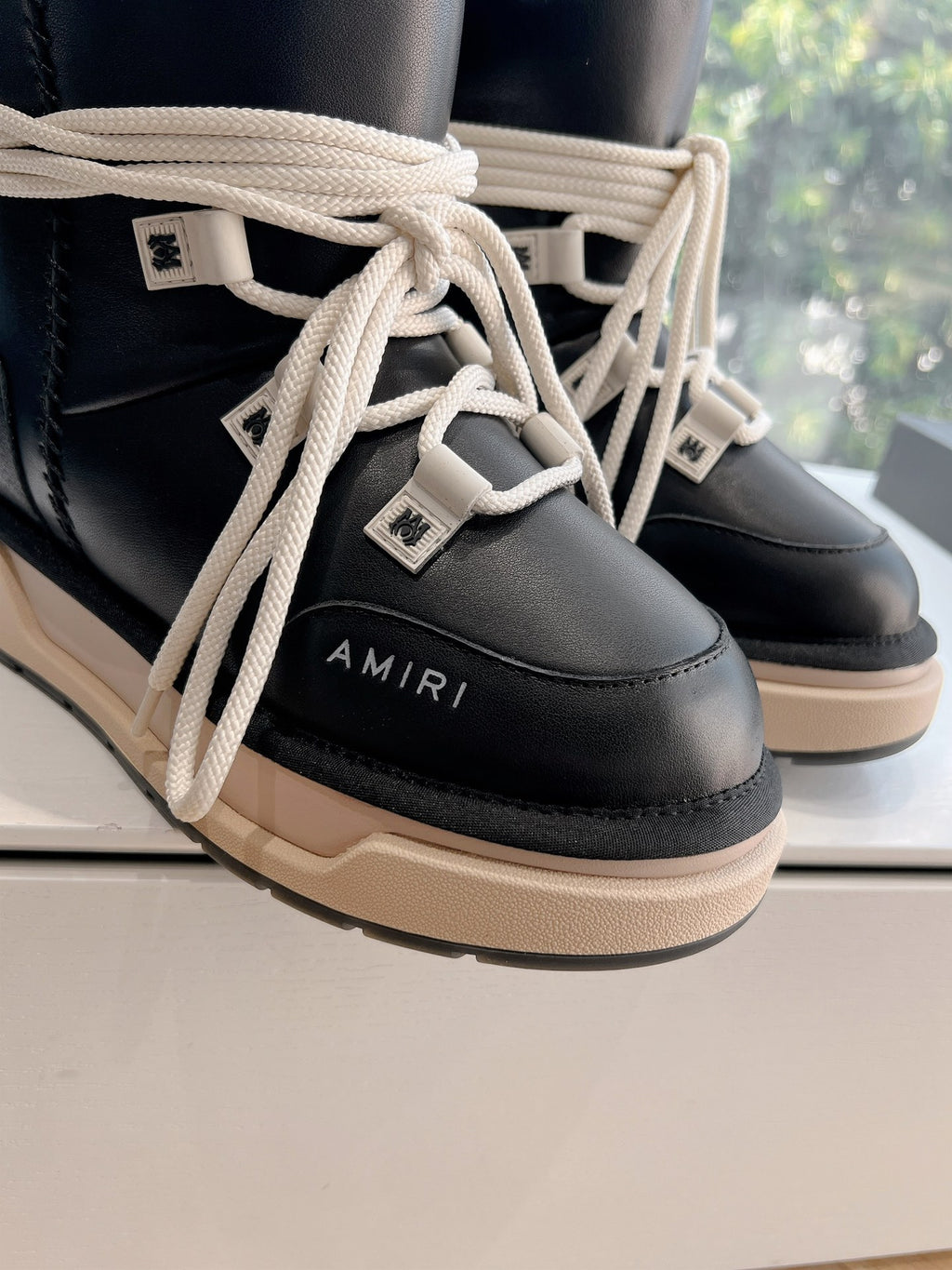 Amiri black high-top sneakers close-up of cream laces and logo patch