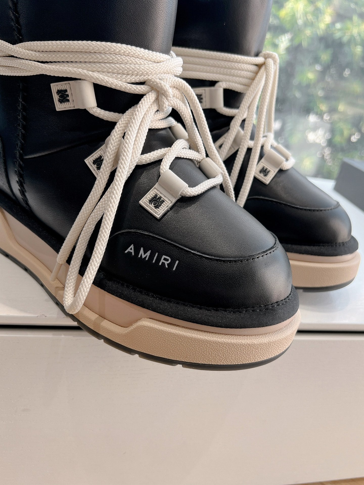 Amiri black high-top sneakers close-up of cream laces and logo patch
