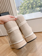 Beige suede boots held by hand; fur-lined cuff and AMIRI logo