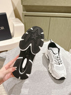 Shoe bottoms of white sneakers with Dior logo, rugged tread and black rubber soles