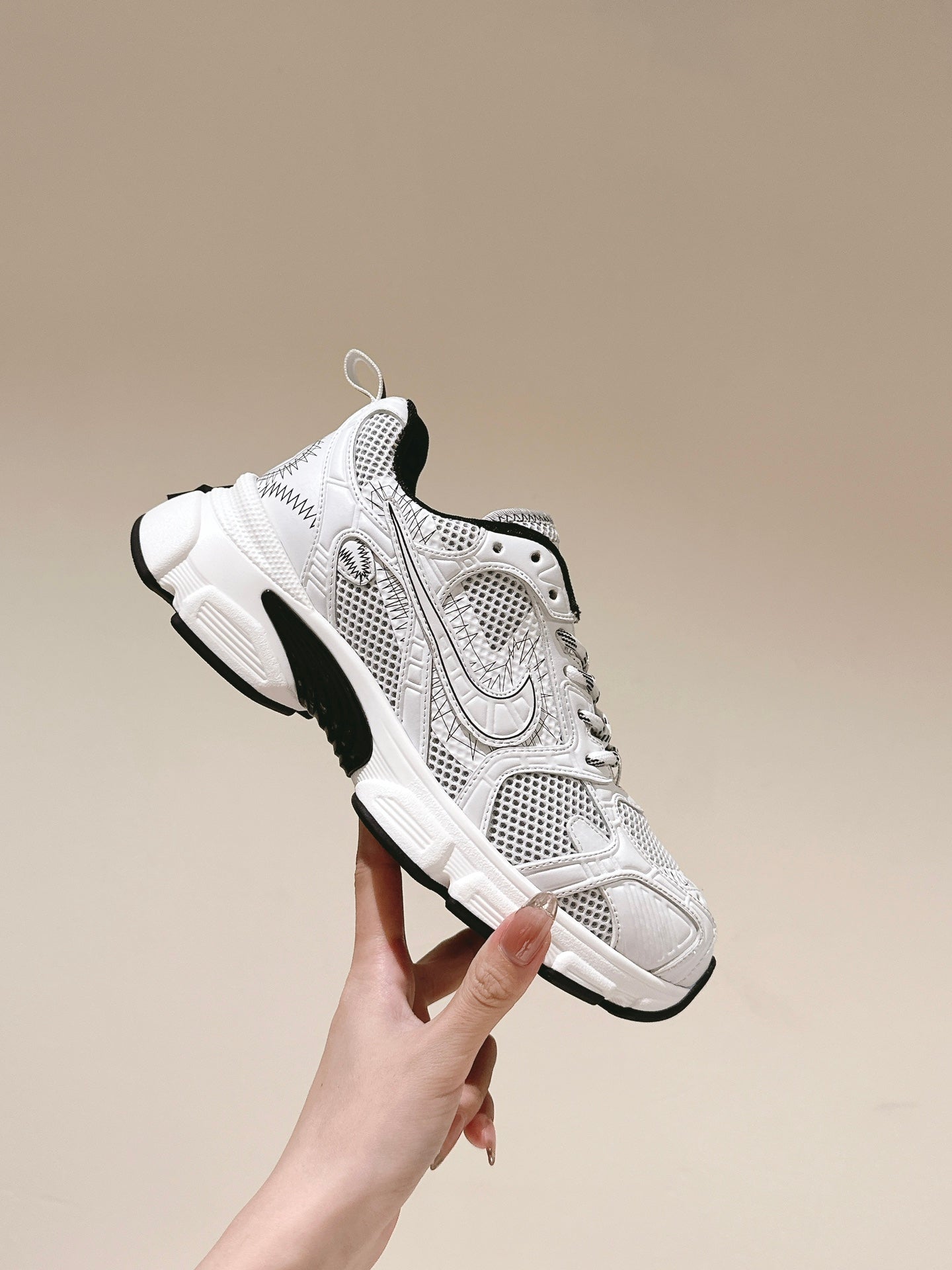 White lace-up sneaker held up: perforated mesh upper with Dior branding