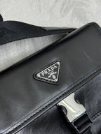Prada bag close-up: black flap with silver logo plaque and stitched edge