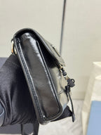 Prada bag side view in black leather with top handle and strap hardware