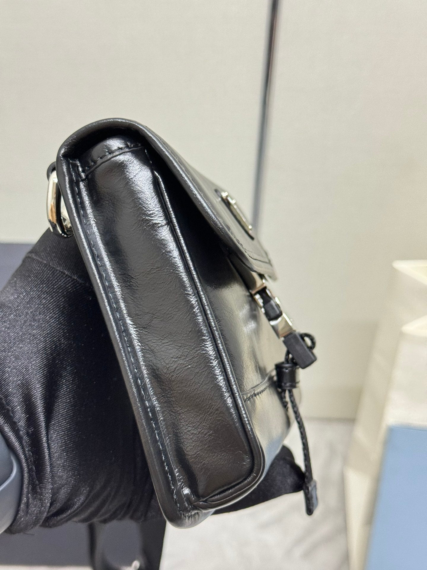 Prada bag side view in black leather with top handle and strap hardware