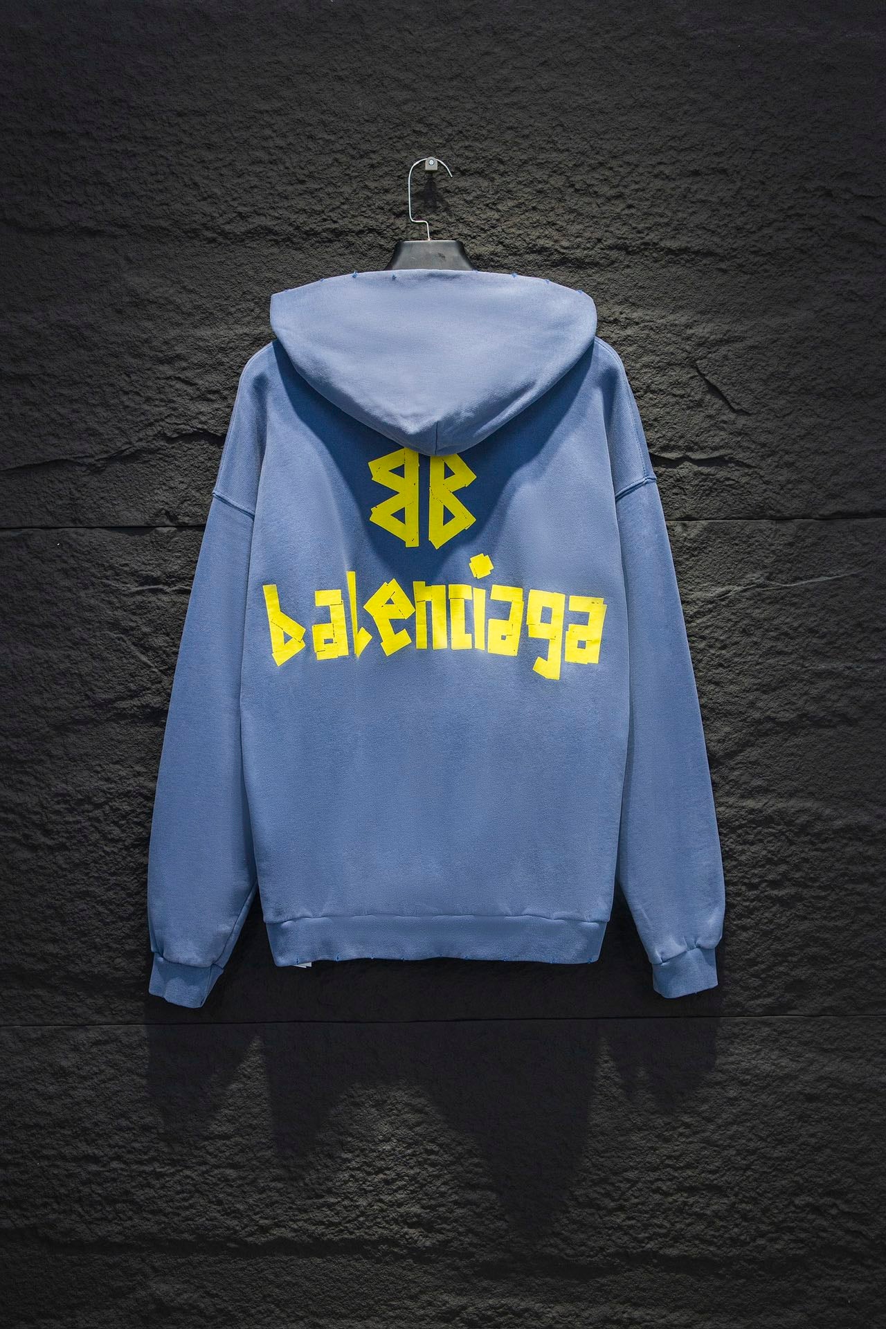 Light blue hoodie with hood, back yellow graphic text, and bright symbol logo on the back