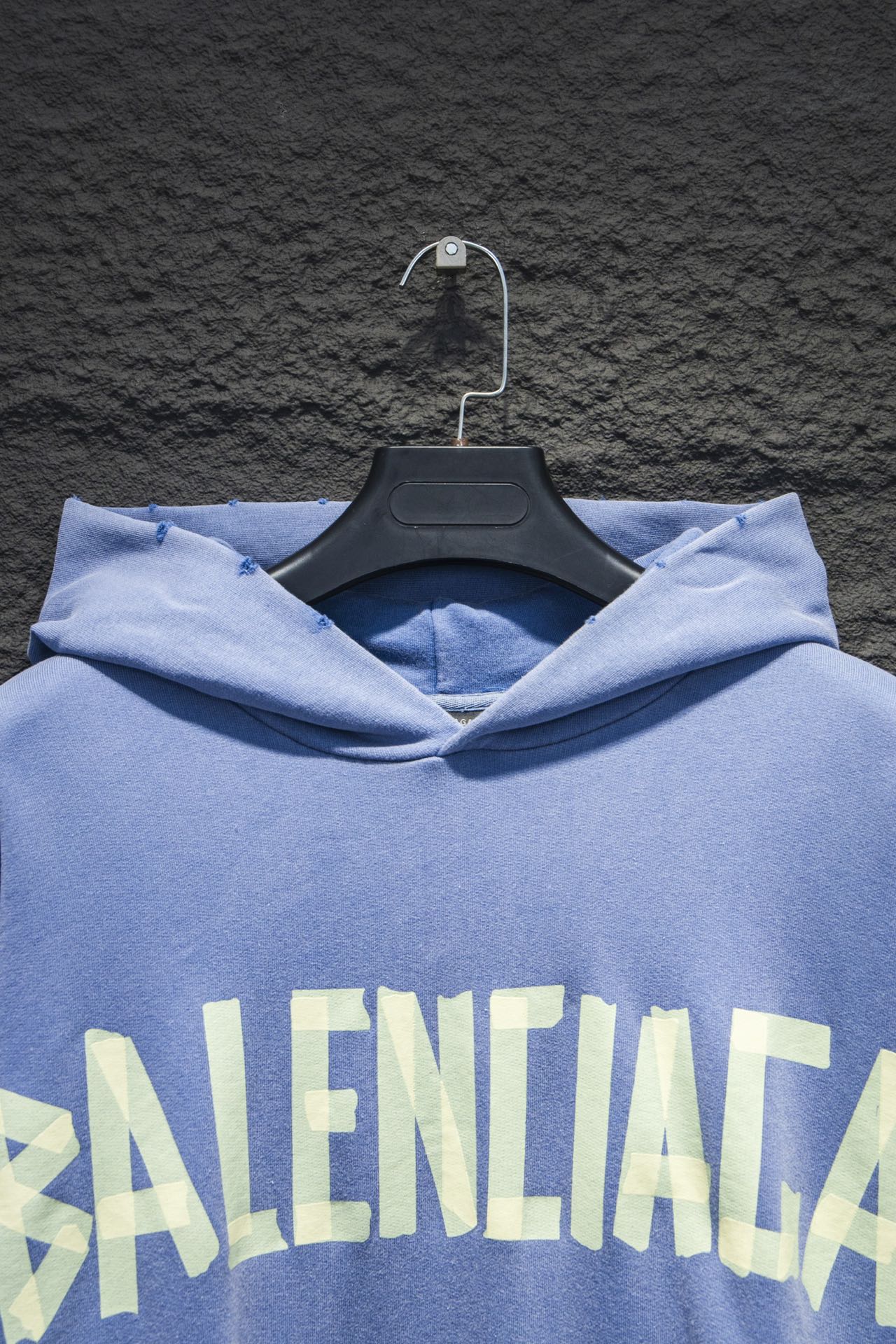 Light blue hoodie hood with interior collar; large front graphic text visible at the chest