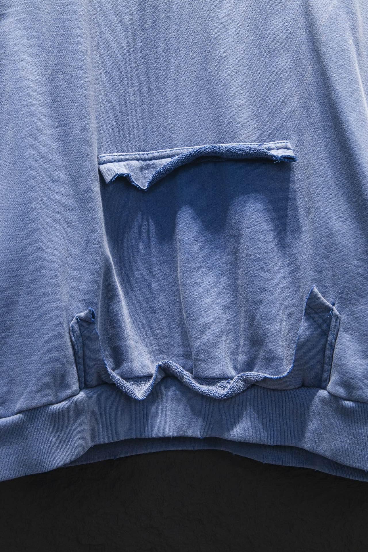 Light blue hoodie front pouch opening with stitched edges and wide kangaroo-style pocket