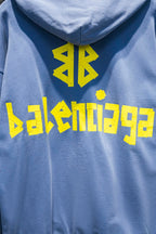 Light blue hoodie back with yellow graphic symbols and stylized text print on the upper back