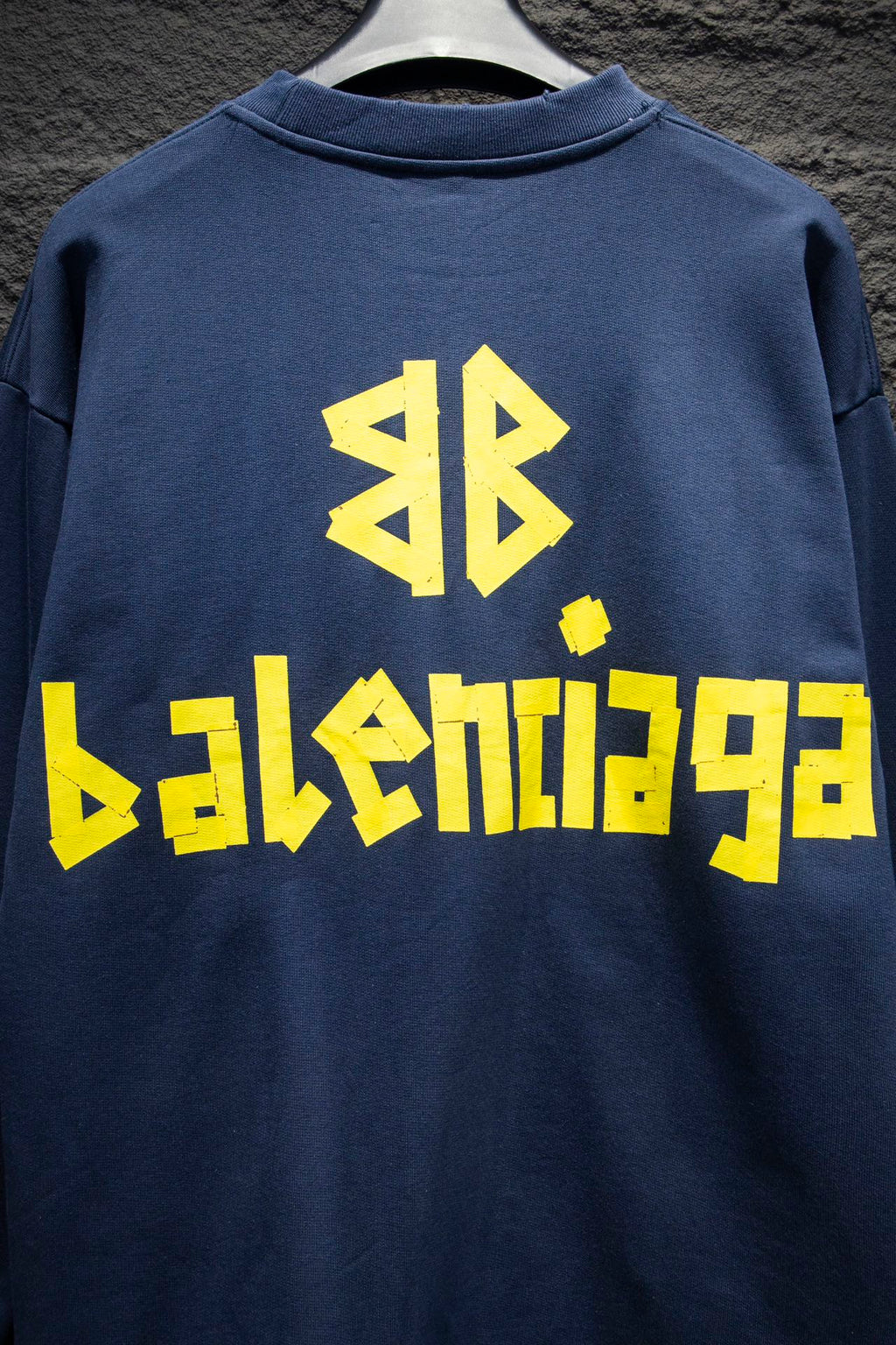 Blue sweatshirt with large yellow Balenciaga-style logo on back