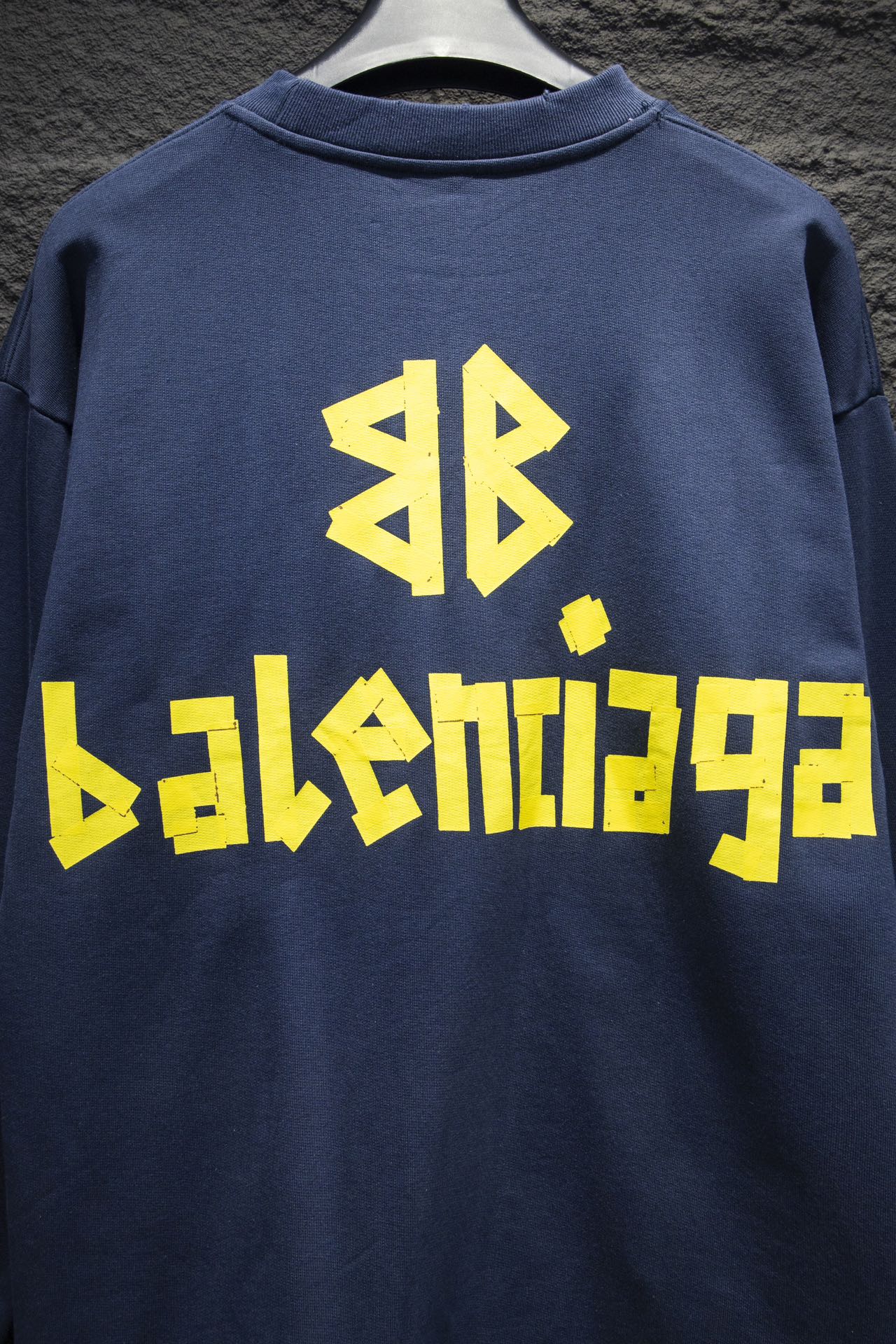 Blue sweatshirt with large yellow Balenciaga-style logo on back