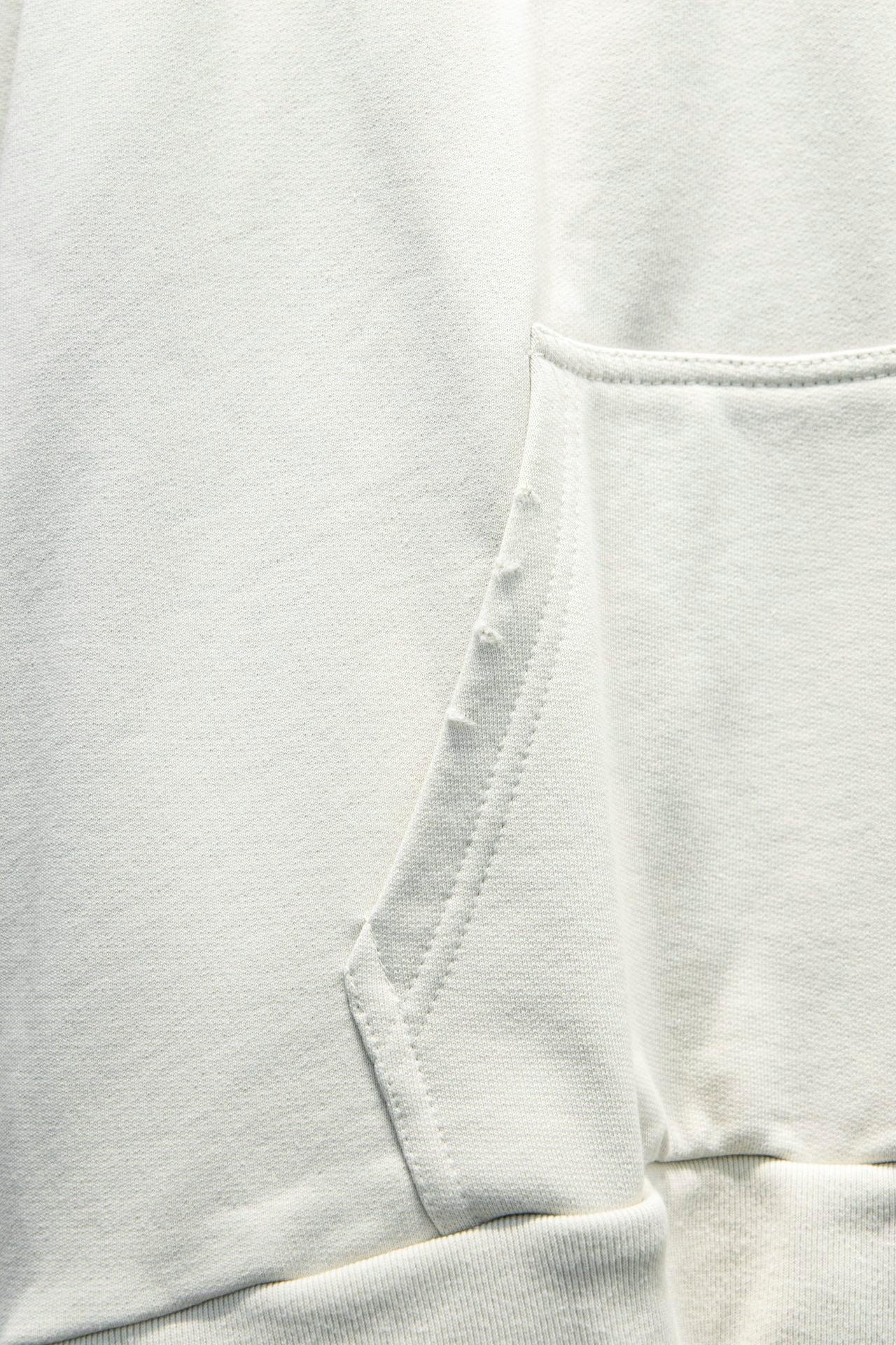 White hoodie fabric with stitched hood seam and drawstring opening