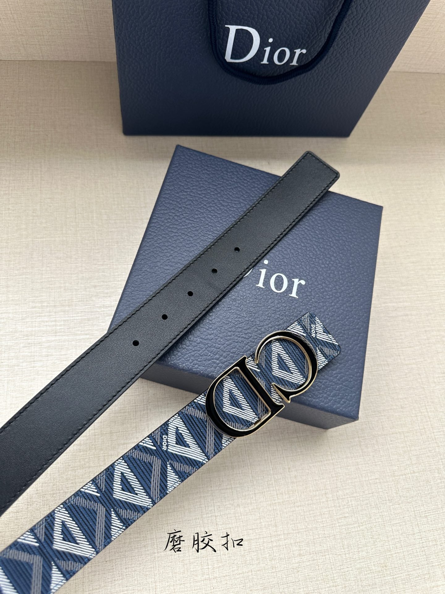 Dior belt flat view: navy strap with holes and blue monogram under gold buckle.
