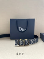 Dior belt resting on navy gift bag: blue monogram strap with gold-tone buckle.