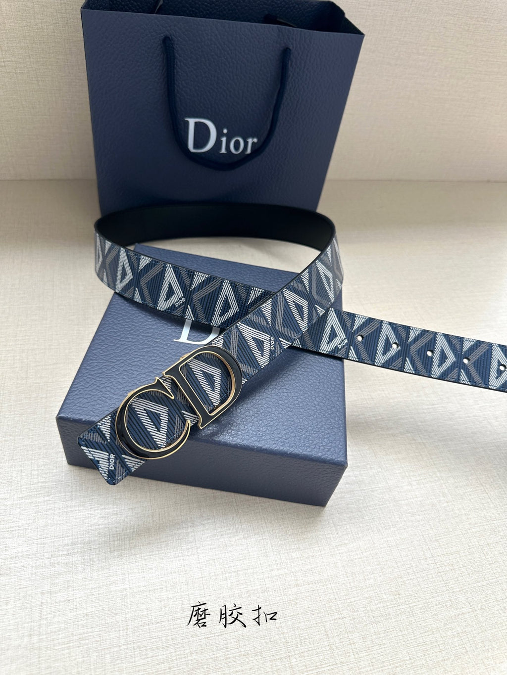 Dior belt with buckle detail: navy geometric monogram strap over blue presentation box.