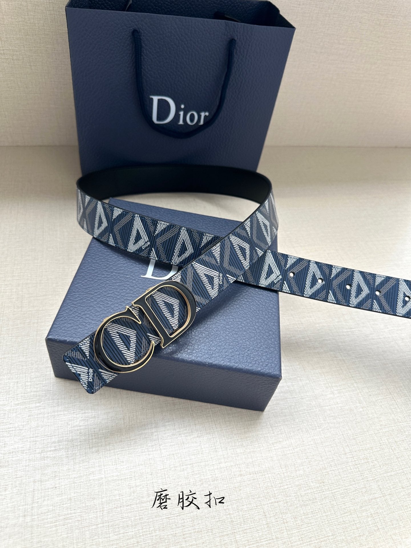 Dior belt with buckle detail: navy geometric monogram strap over blue presentation box.
