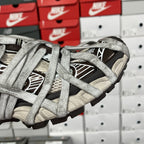 Gray sneakers side view with crisscross laces and black striped window panels