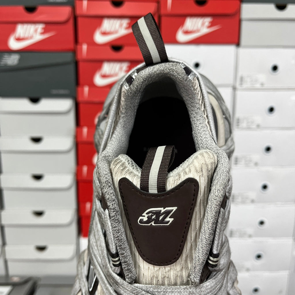Gray sneaker heel view with dark logo patch and ribbed strap detail