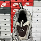 Gray sneaker heel view with dark logo patch and ribbed strap detail