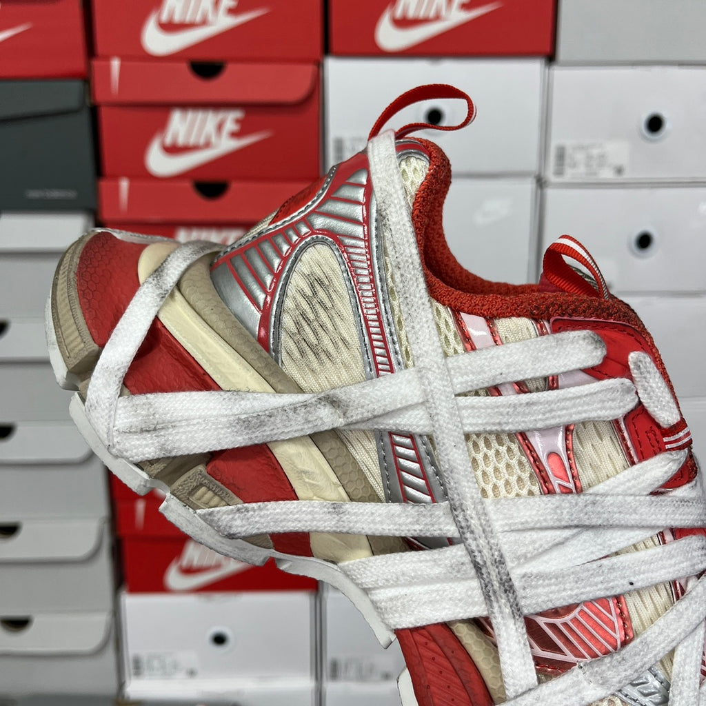 Unisex sneaker front-side view with red suede heel, beige panels, and white laces